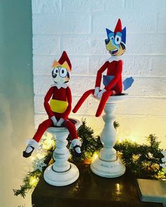 two red and yellow stuffed animals sitting on top of white pedestals