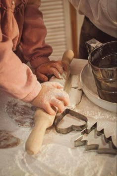 a person is making dough on a table with cookie cutters in front of them