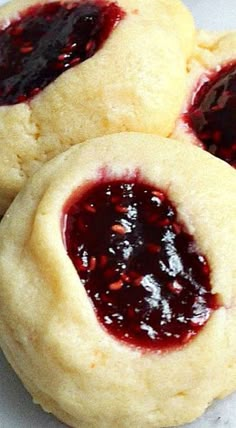 three cookies with jelly filling on them sitting on a white table top next to each other