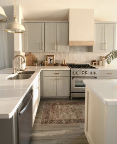 a kitchen with white cabinets and an area rug on the floor in front of the stove