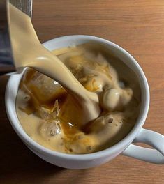 a spoon is being used to scoop some liquid into a cup filled with ice cream