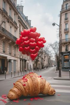 a croissant with red heart shaped balloons attached to it