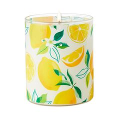 a white candle with yellow lemons and leaves on it, sitting in front of a white background