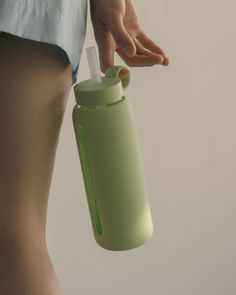 a person is holding a green water bottle