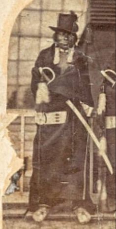 an old black and white photo of a man in costume holding two large shovels