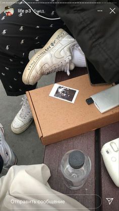 a person sitting on a bench next to a box with an open laptop and other items