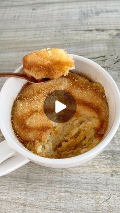 a bowl filled with food sitting on top of a wooden table next to a spoon