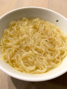 a white bowl filled with noodles on top of a wooden table