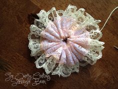 a close up of a flower on top of a wooden table with crochet lace