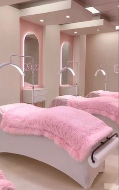 two beds with pink blankets and mirrors in a room that has lights on the ceiling