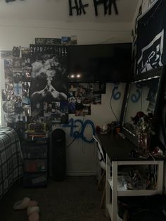 a bedroom with posters on the wall and a desk in front of it, next to a bed