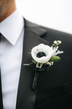 a man wearing a black suit and white flower boutonniere