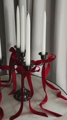 a candle holder with six candles wrapped in red ribbon