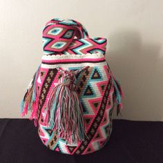 a pink and blue bag sitting on top of a black table next to a white wall