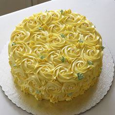 a cake with yellow frosting and roses on it sitting on a white doily