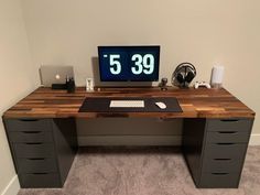 a computer desk with a clock on the wall above it and drawers below it, in front of a carpeted floor