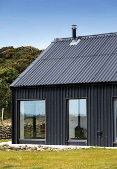 a black house with two windows and a metal roof