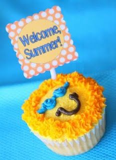 a cupcake with a welcome summer sign on top is sitting on a blue tablecloth