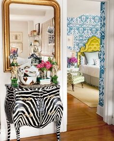 a zebra print dresser and mirror in a room with blue wallpaper, gold framed mirror, and white walls