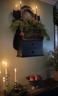 a table with candles, apples and pine cones on it in front of a clock