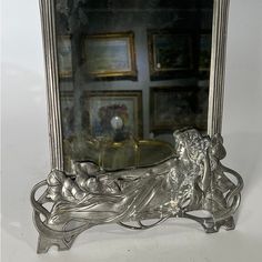 an ornate silver framed mirror sitting on top of a table