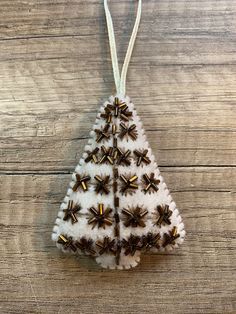 a christmas tree ornament hanging on a wooden table with white and brown decorations