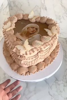 a hand is holding a cake with a photo on it and butterflies around the edges