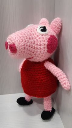 a crocheted pig stuffed animal is standing on a shelf with its eyes wide open