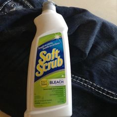 a bottle of soft scrub sitting on top of a pair of jeans