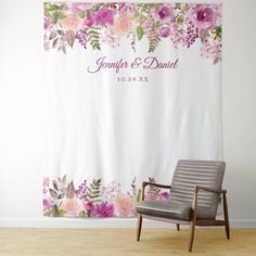 a chair sitting in front of a floral wall hanging