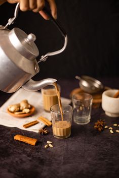 a person pours coffee from a teapot into a glass on top of a table