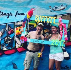 a man and woman standing in front of a mural holding a sign that says buffet