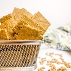 a metal basket filled with crackers on top of a white table next to a napkin