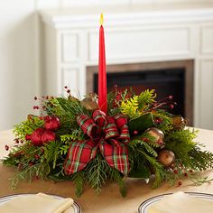 a christmas centerpiece on a dining room table with a lit candle in the center