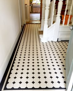 a hallway with black and white tile flooring next to a stair case in a house