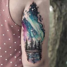 a person with a tattoo on their arm that has an image of the sky and trees