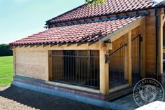 a wooden building with a red tiled roof and gated in area next to it