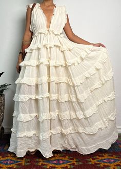 a woman wearing a white dress standing in front of a wall with her hands on her hips