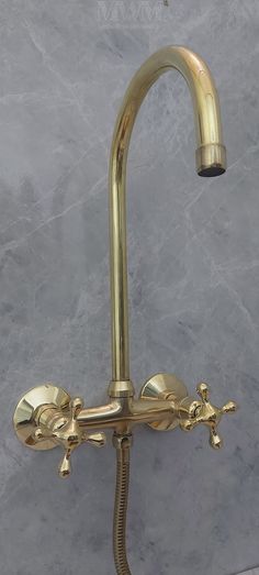 a gold faucet with two hands on the side and a hose attached to it