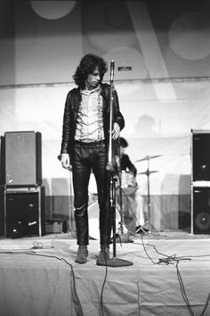 a man standing on top of a stage holding a microphone in front of two other men