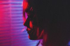 a woman's profile in front of a purple and red light