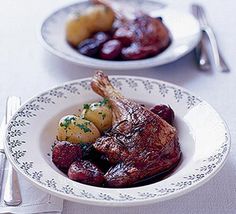 two plates filled with meat and potatoes on top of a table next to silverware