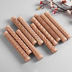 six pieces of carved wood sitting next to each other on a gray surface with cherry blossoms in the background