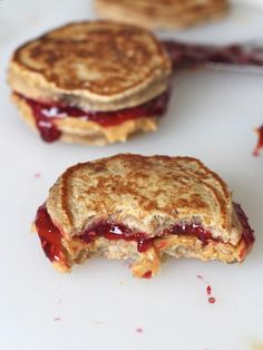 two grilled sandwiches on a white plate with raspberry sauce in between them