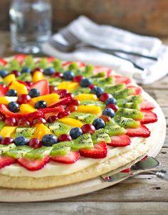 a pizza with fruit on it sitting on top of a wooden table