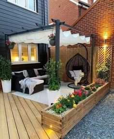 an outdoor living area with wooden decking and potted plants on the side of it