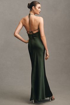 a woman in a long green dress is standing back to back with her hands on her hips