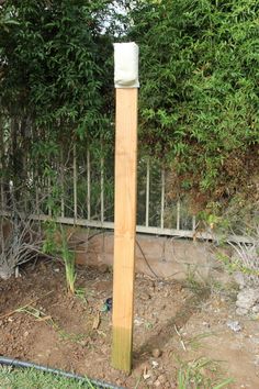 a tall wooden pole sitting in the middle of a yard next to a fence and trees