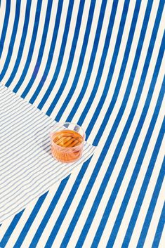 a bowl of food sitting on top of a blue and white striped table cloth next to an orange cup