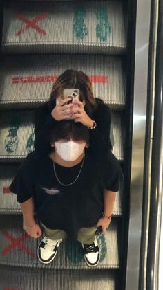 a woman standing on an escalator with her face covered by a mask